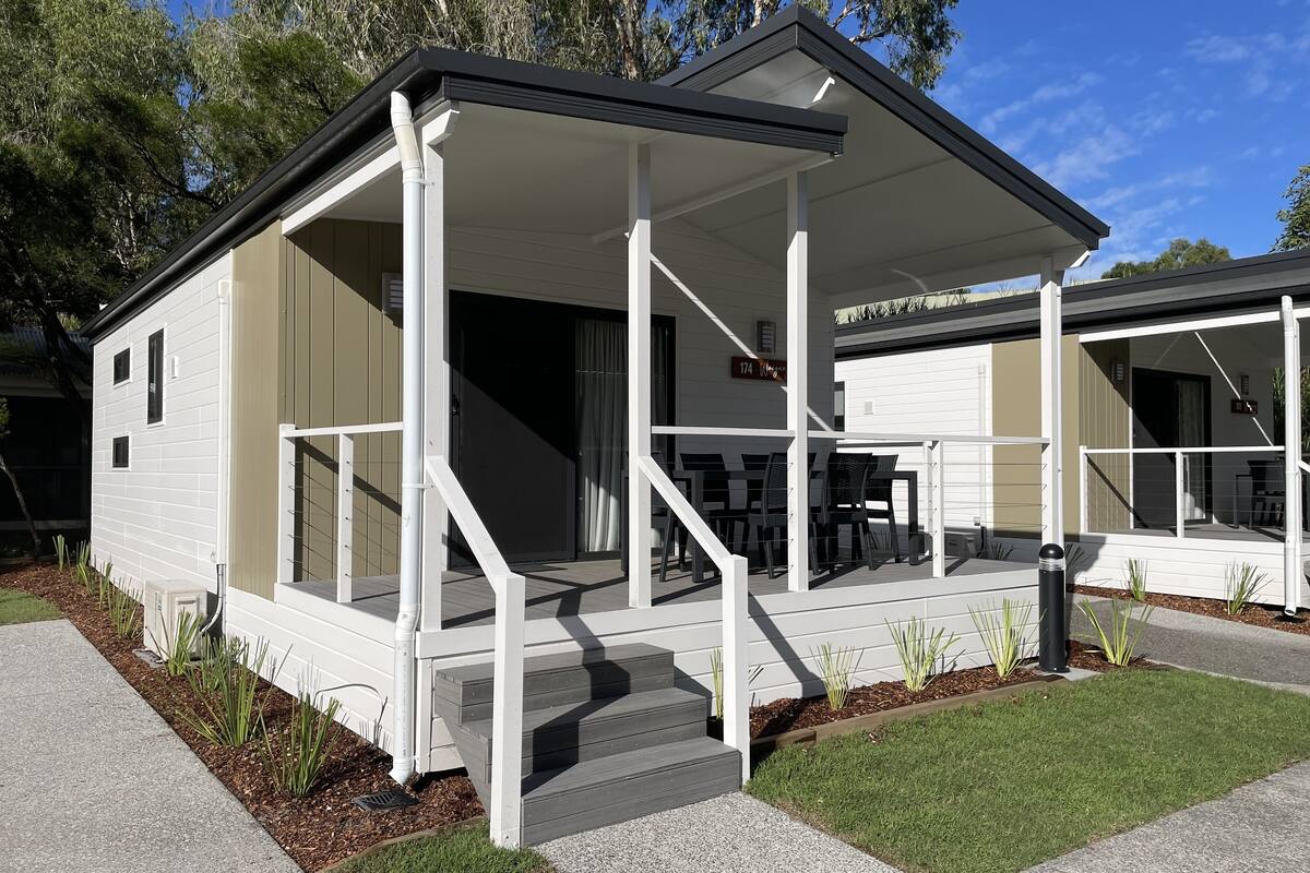 A modern single-story house with a covered porch, a small front yard, and a mailbox.