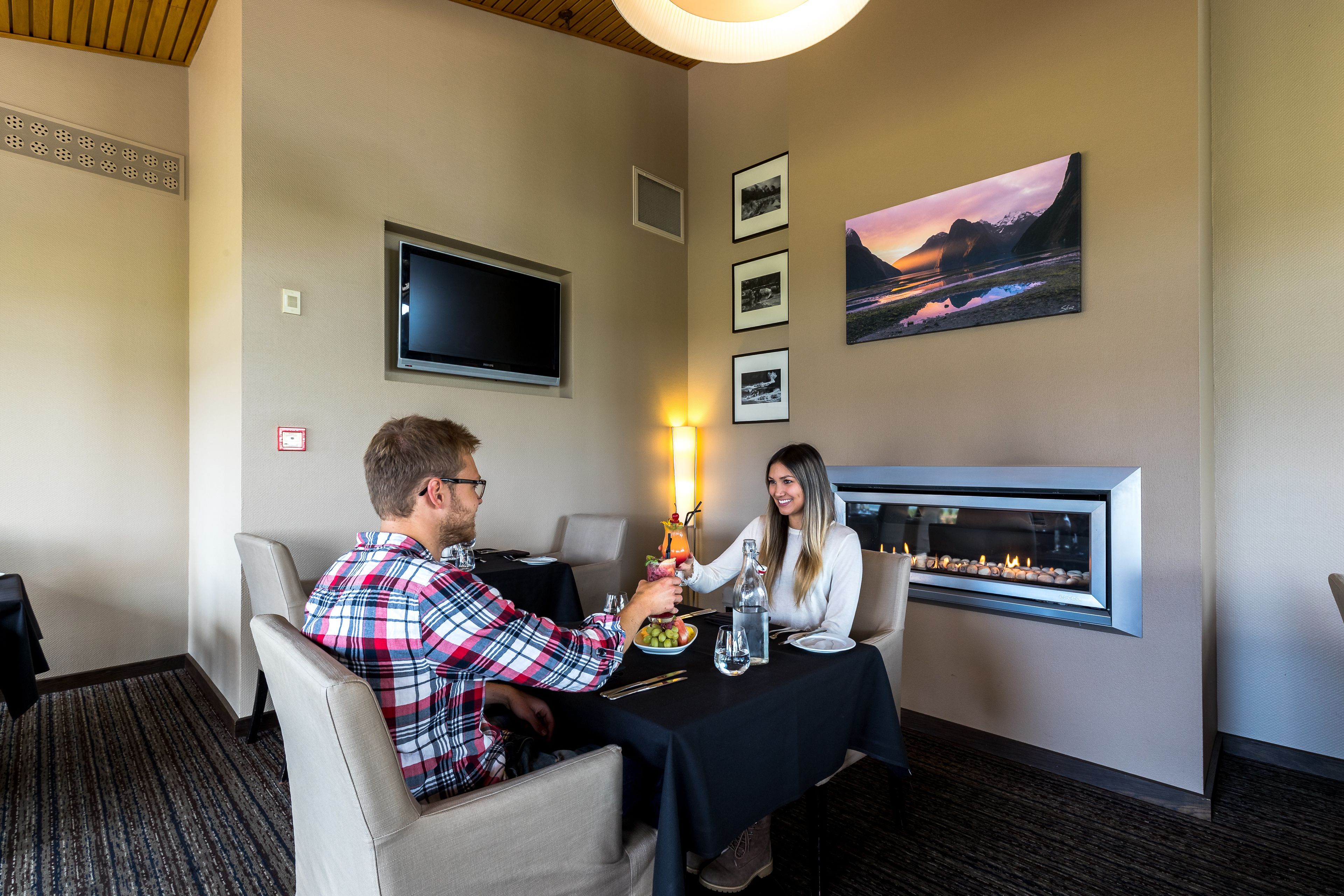 Un comedor con chimenea, televisor de pantalla plana y cuadros en la pared.