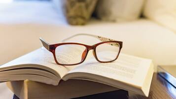 A book with glasses on top, placed on a wooden surface.