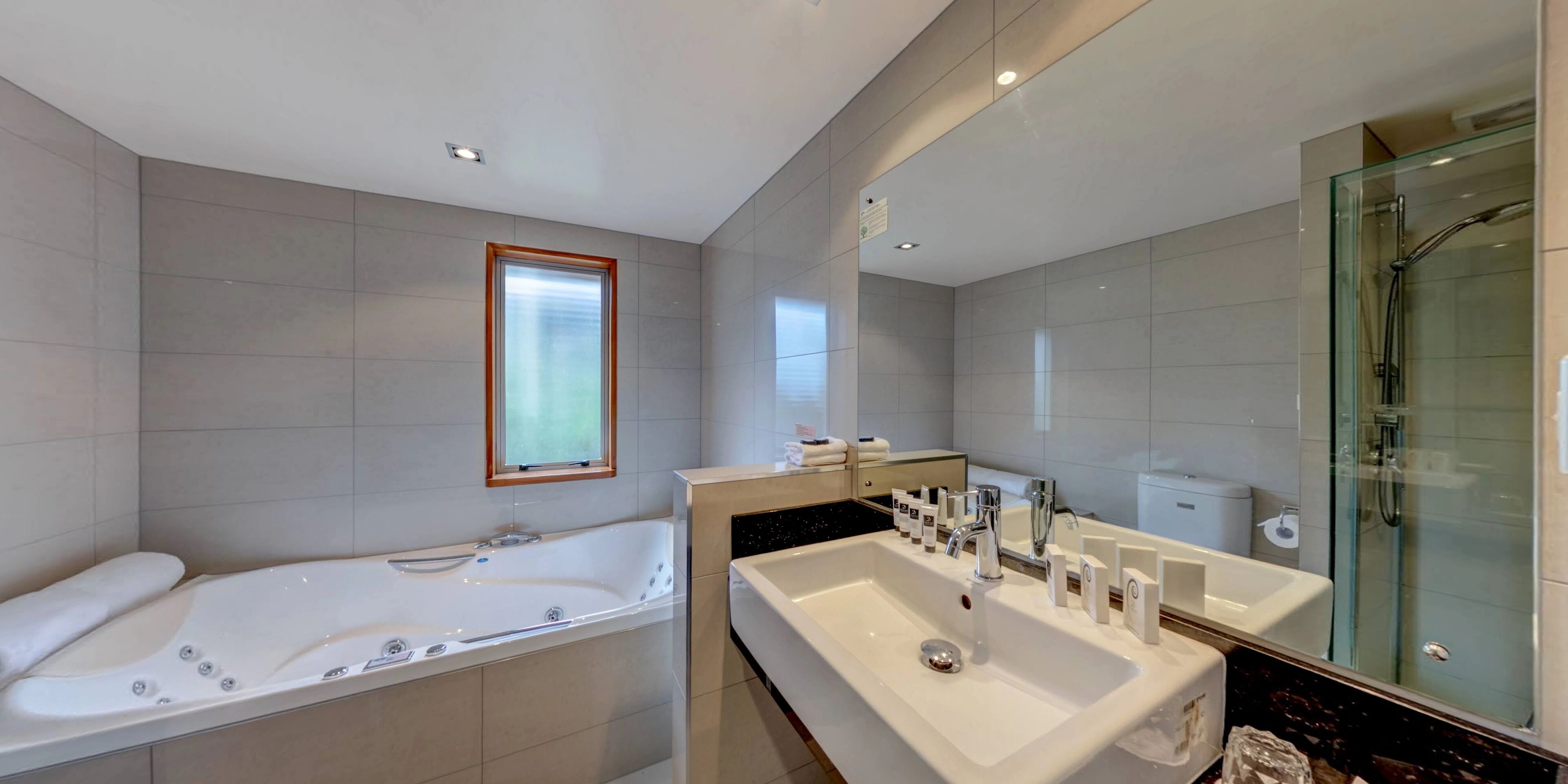A modern bathroom with a large bathtub, a separate shower area, and a vanity with a sink and mirror.