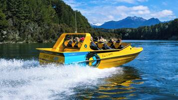 A yellow boat with passengers on a lake surrounded by mountains.