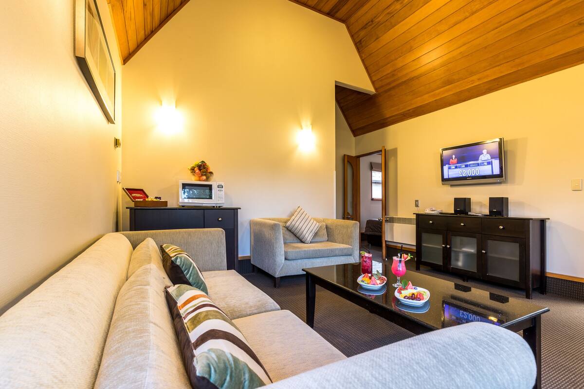 A modern living room with a sofa, armchairs, a coffee table, a TV, and a microwave.
