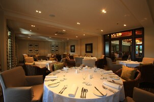 A restaurant with round tables set for dining, featuring white tablecloths and silverware.