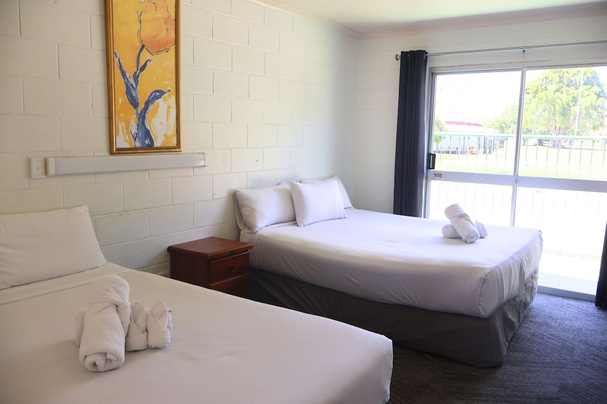 Habitación de hotel con dos camas, un cuadro en la pared y una ventana con vistas al exterior.
