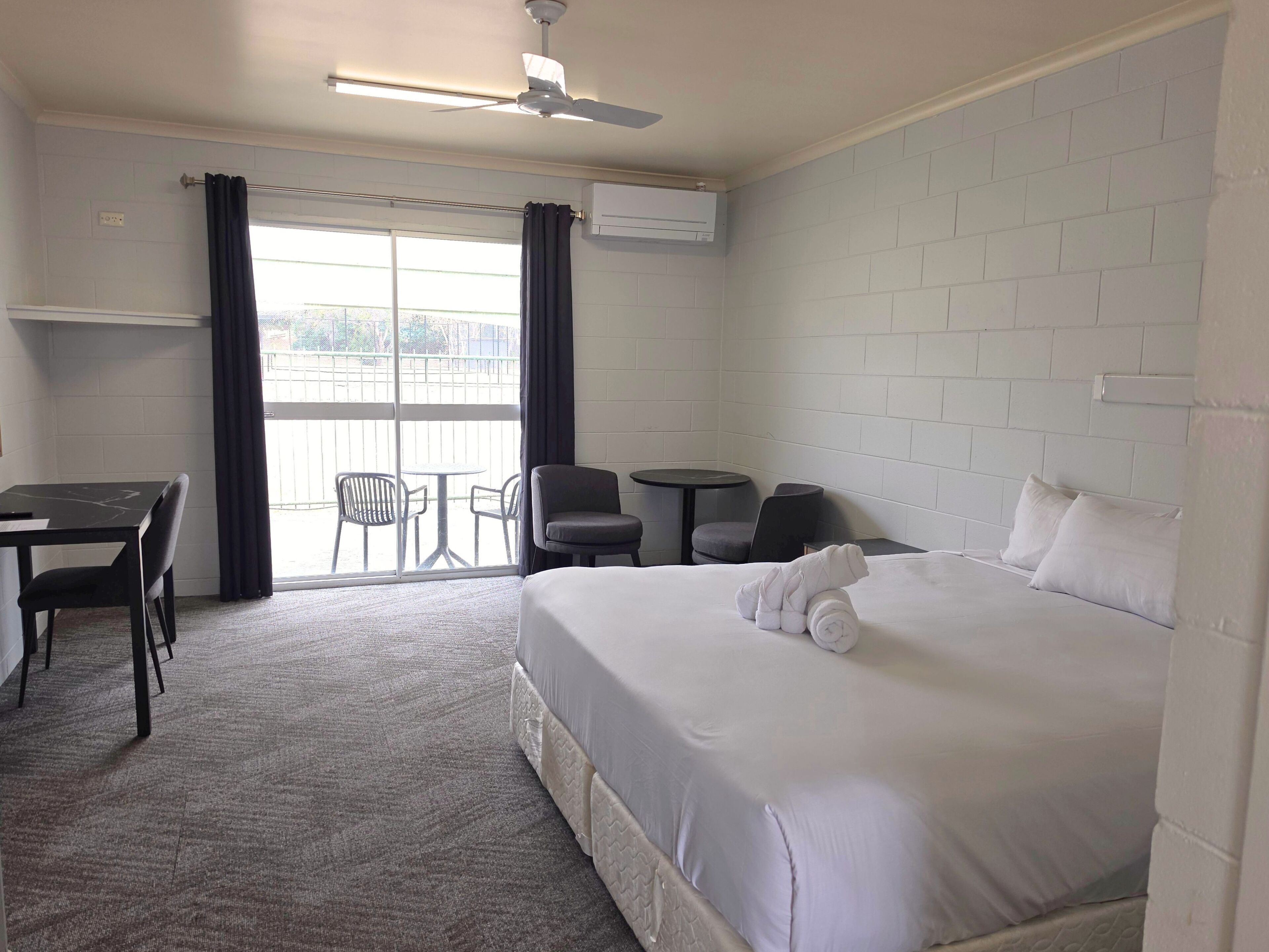 Ein Hotelzimmer mit Bett, Schreibtisch, Stuhl, kleinem Tisch und einem Balkon mit Blick.
