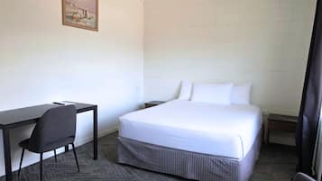 Una camera d'albergo con un letto, una scrivania, una sedia e un quadro appeso al muro.