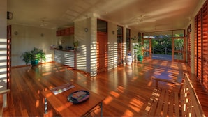 Une pièce spacieuse dotée d’un plancher en bois, de grandes fenêtres et d’un coin repas avec une table et des chaises.