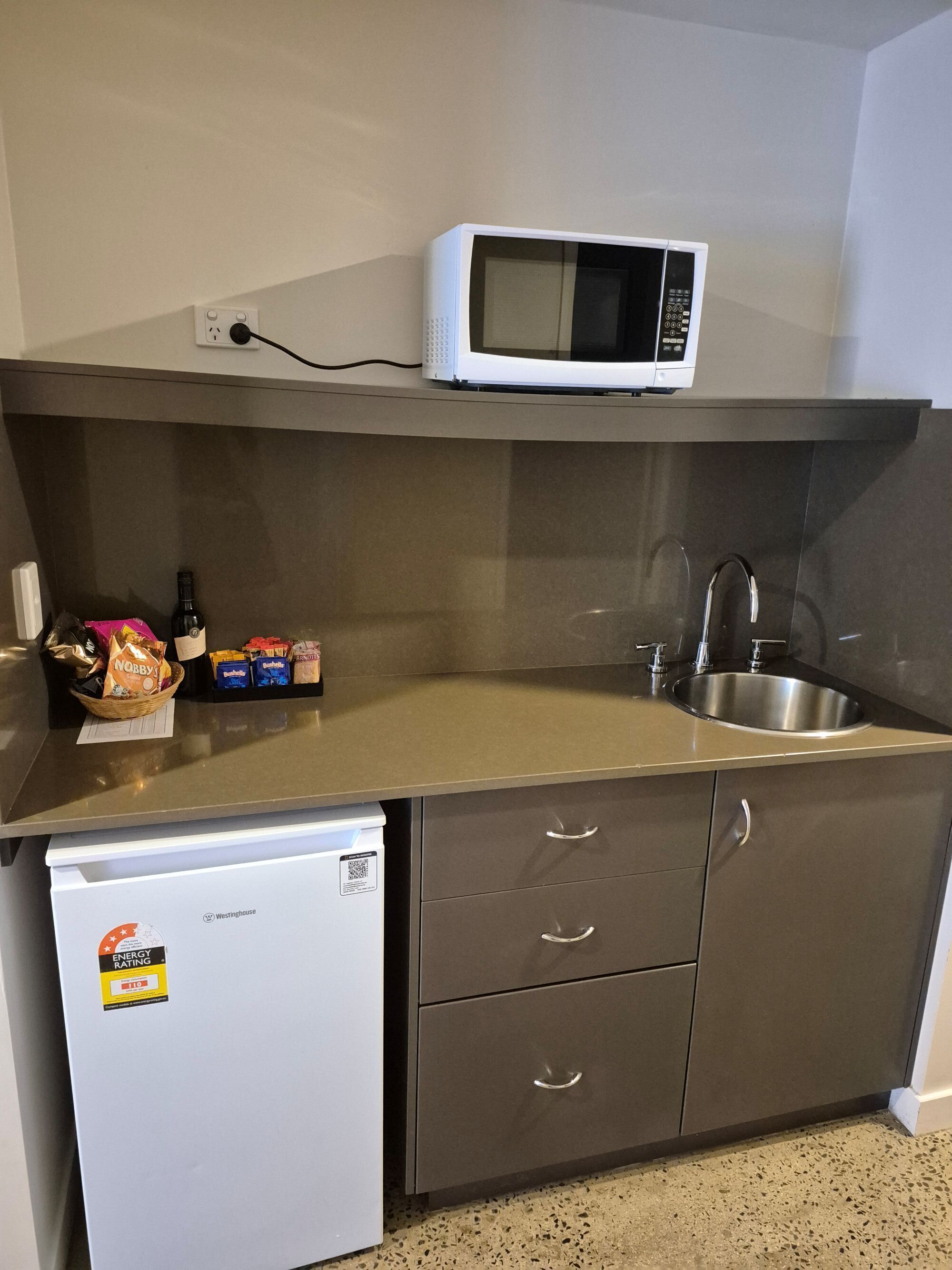 A compact kitchen with a microwave, sink, and a small refrigerator.