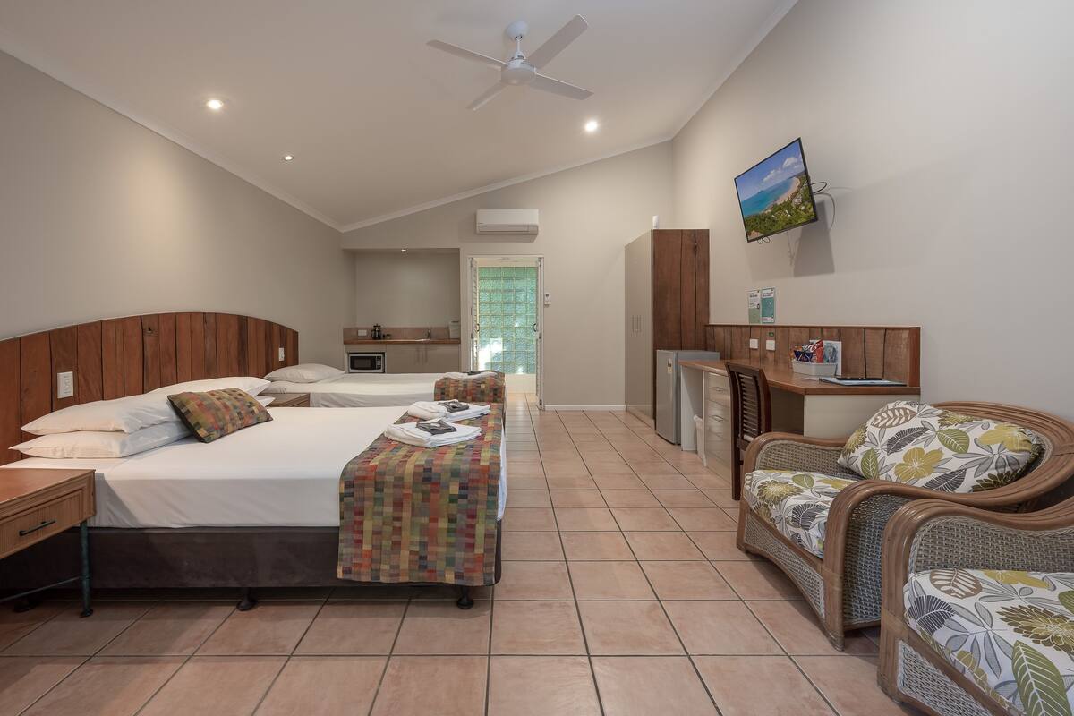 A hotel room with a bed, a desk, a chair, a television, and a view of the outdoors.