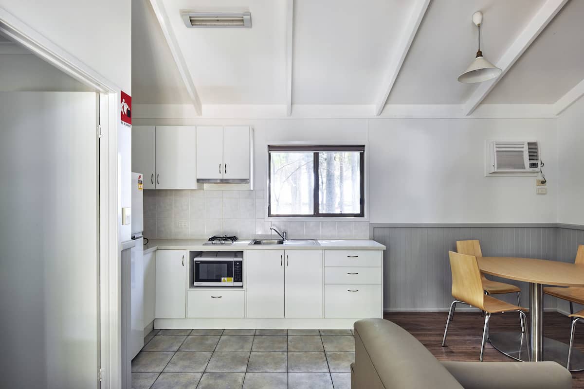 A modern kitchen with white cabinets, a microwave, and a window above the sink.