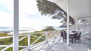 Une terrasse en bois avec une balustrade blanche donnant sur l’océan.