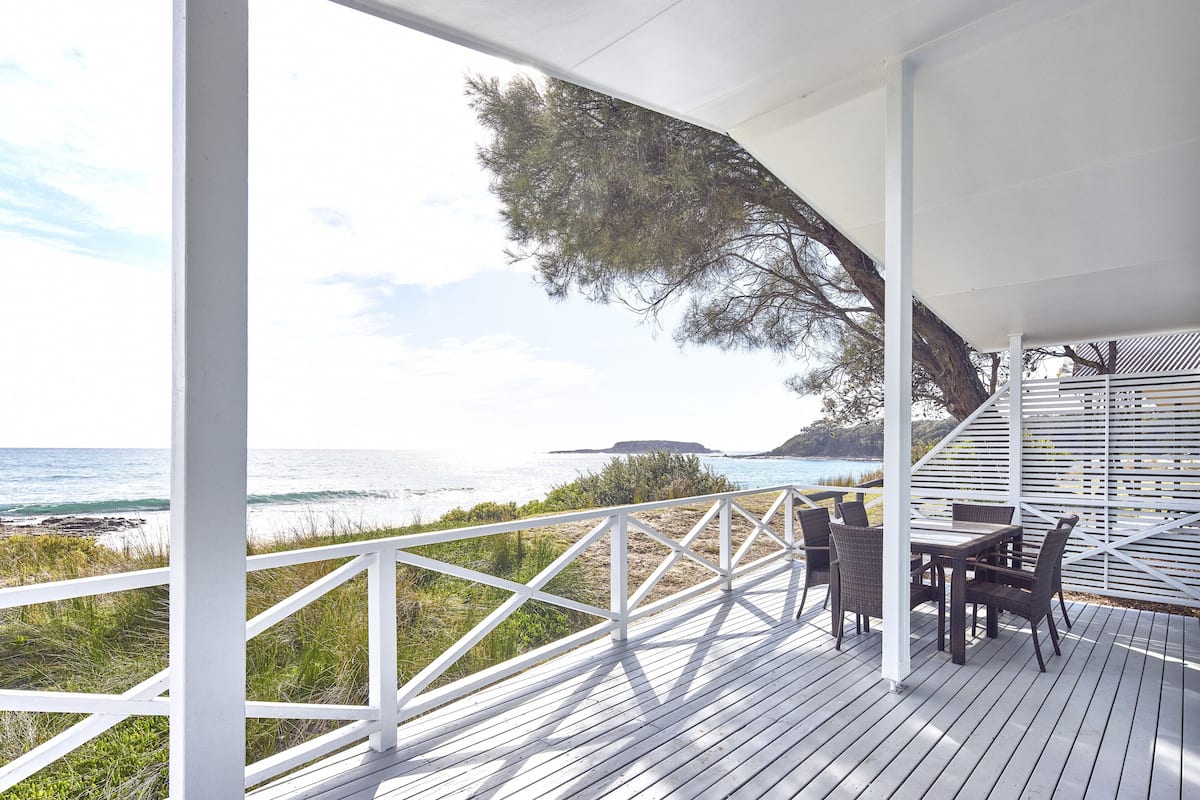 A wooden deck with a white railing overlooking the ocean.