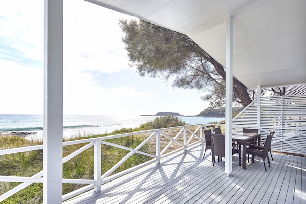 A wooden deck with a white railing overlooking the ocean.