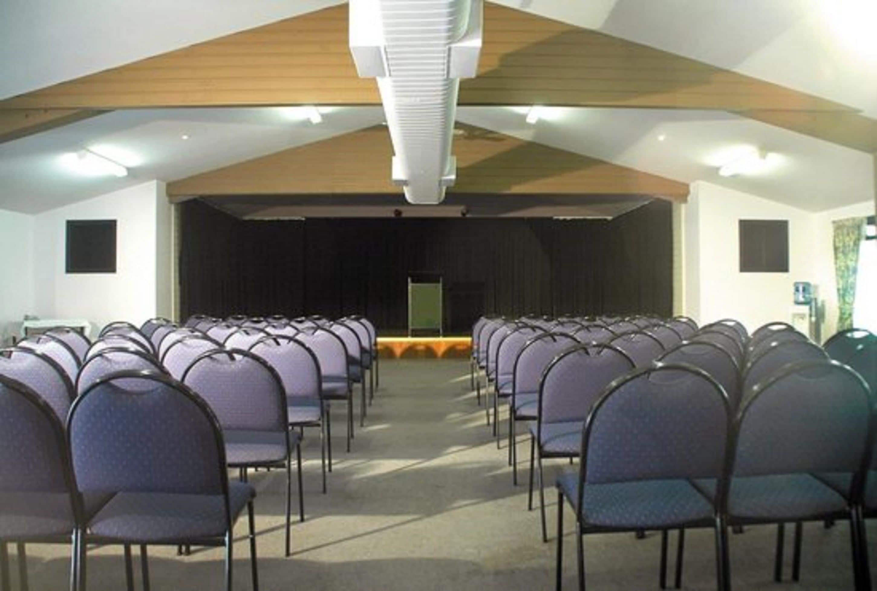 A conference room with rows of chairs facing a stage.