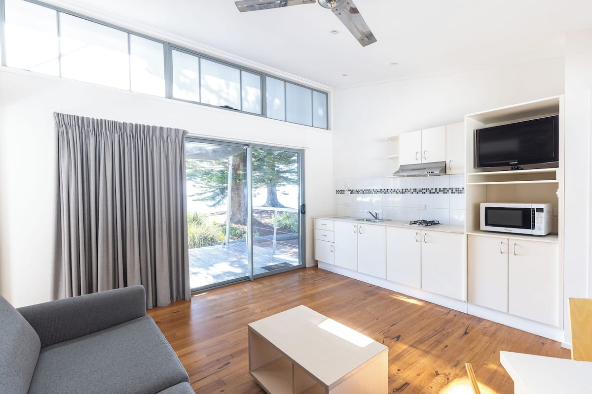 A modern kitchen with white cabinets, a microwave, and a large window.