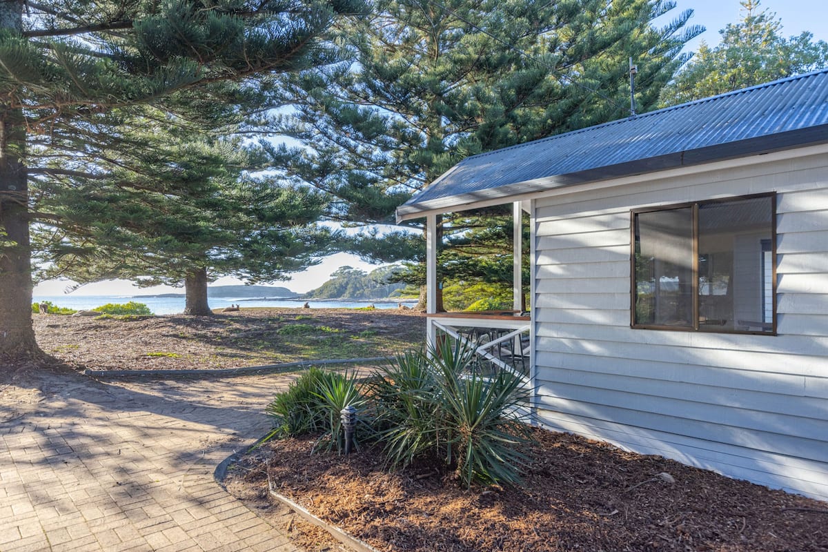 A white building with a covered porch and a view of the ocean.