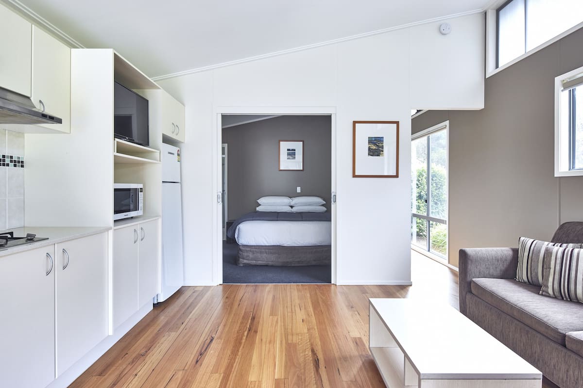A modern, open-plan living space with a kitchen, a dining area, and a bedroom.