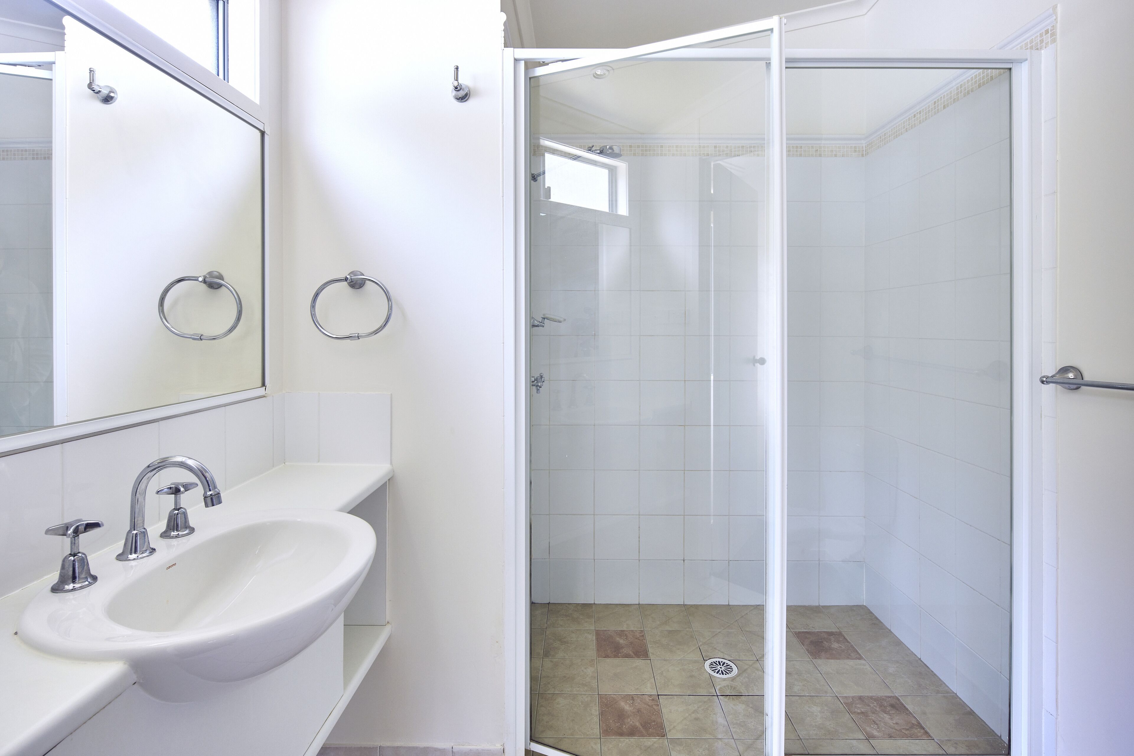 A bathroom with a white sink, mirror, and glass shower enclosure.