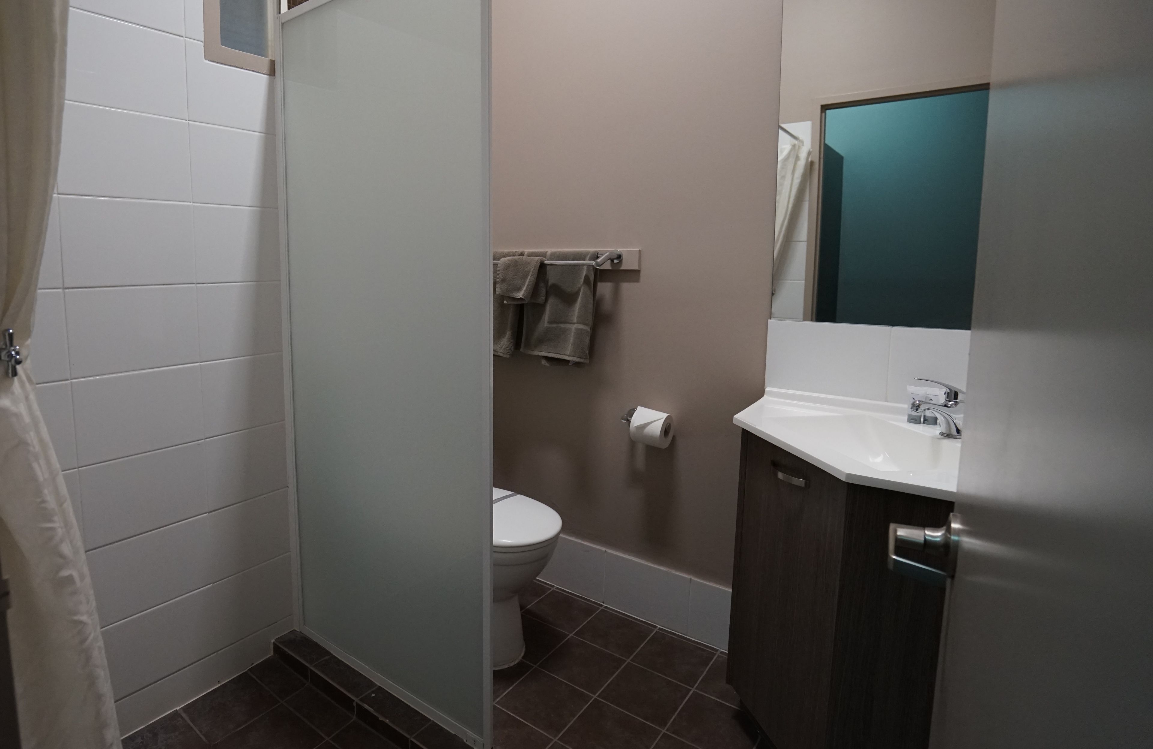 A bathroom with a toilet, a sink, and a mirror.