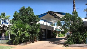 Un motel con entrada cubierta, palmeras y el letrero de Blue Stone Motor Inn.