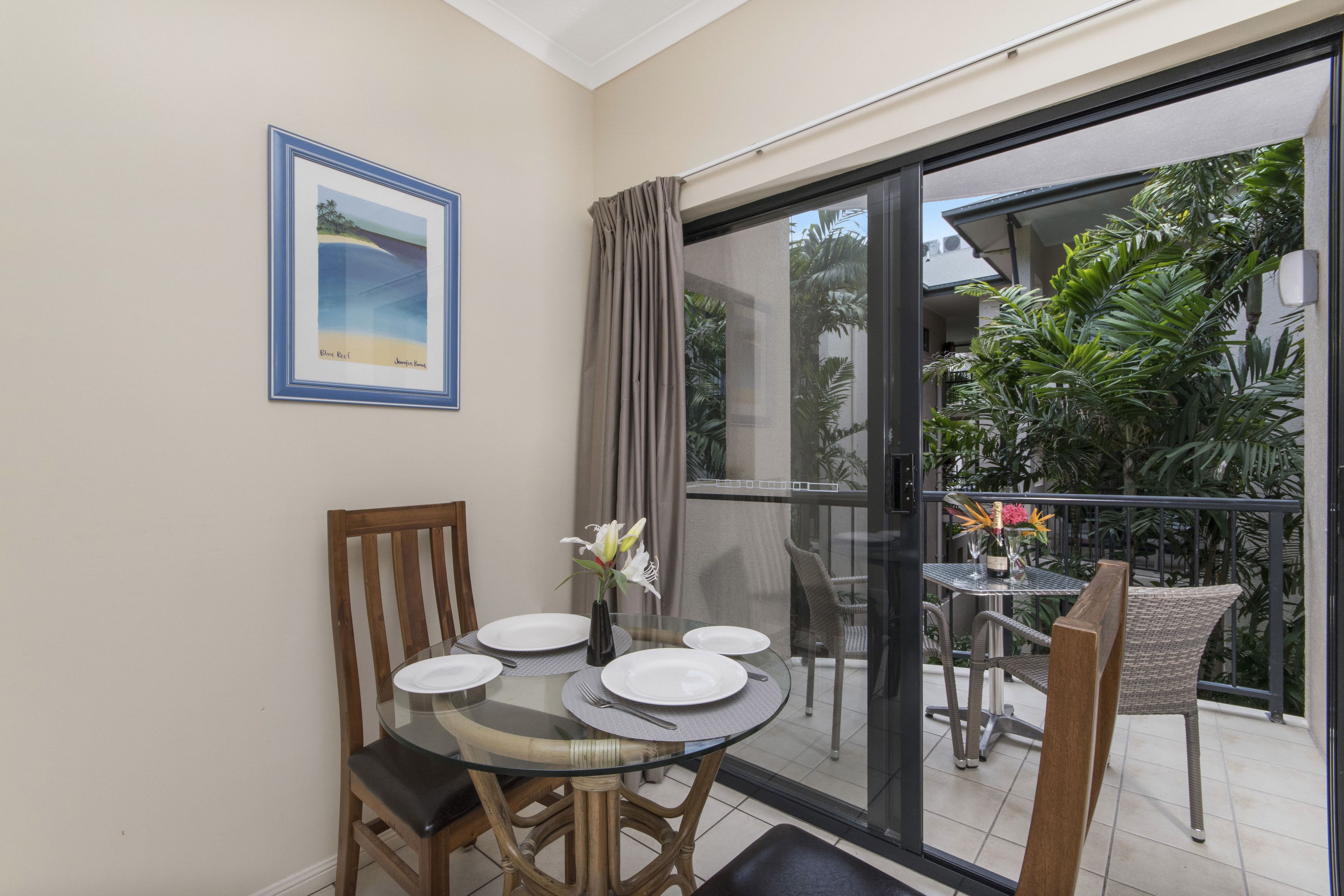 A dining area with a glass table, chairs, and a framed picture on the wall.