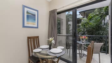 A dining area with a glass table, chairs, and a framed picture on the wall.