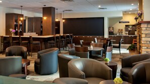 A modern lounge area with leather seating, a bar, and a large screen. - Clearwater Suite Hotel (Fort McMurray)