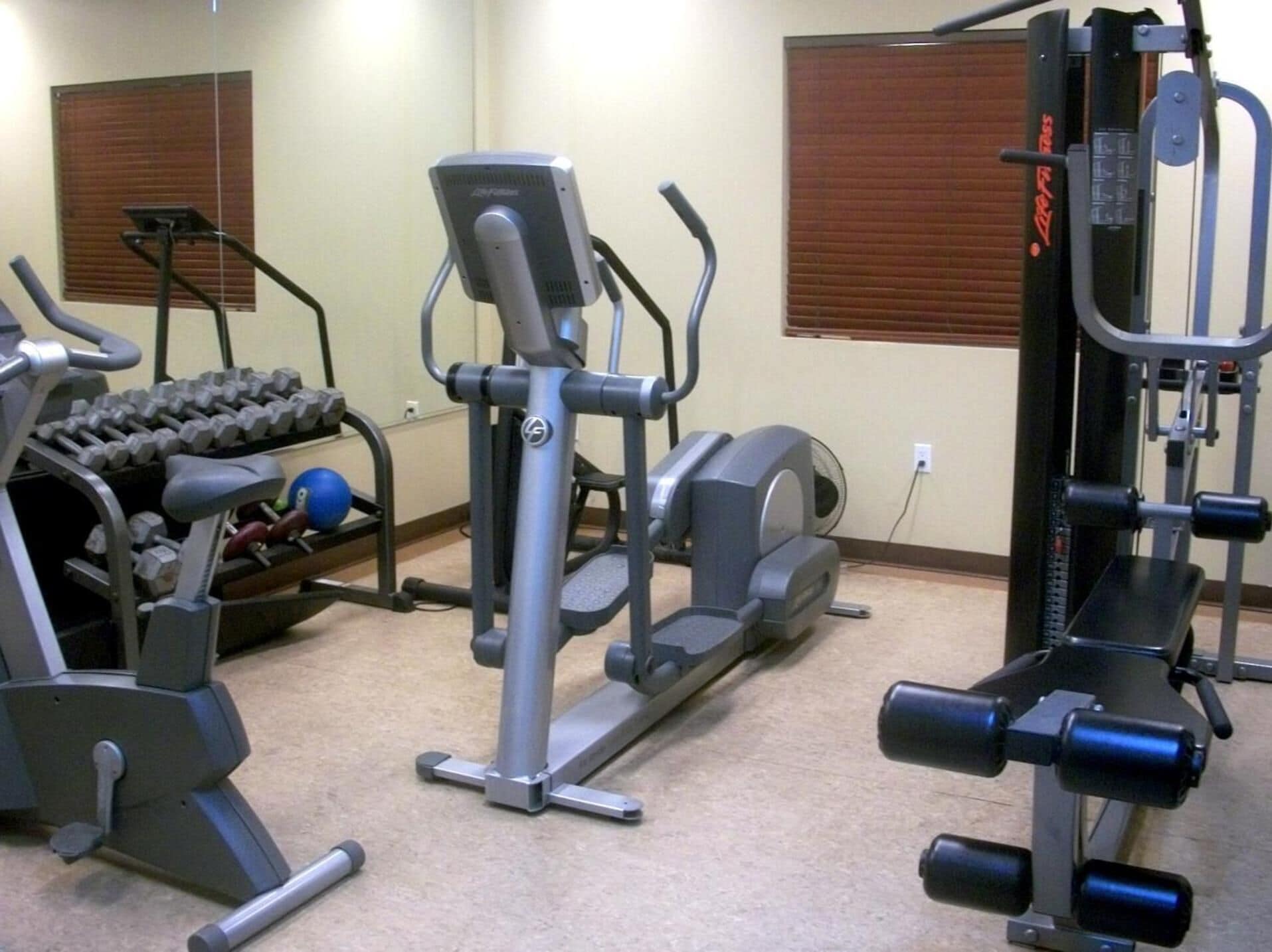 A gym with various exercise equipment including treadmills, weight machines, and dumbbells.