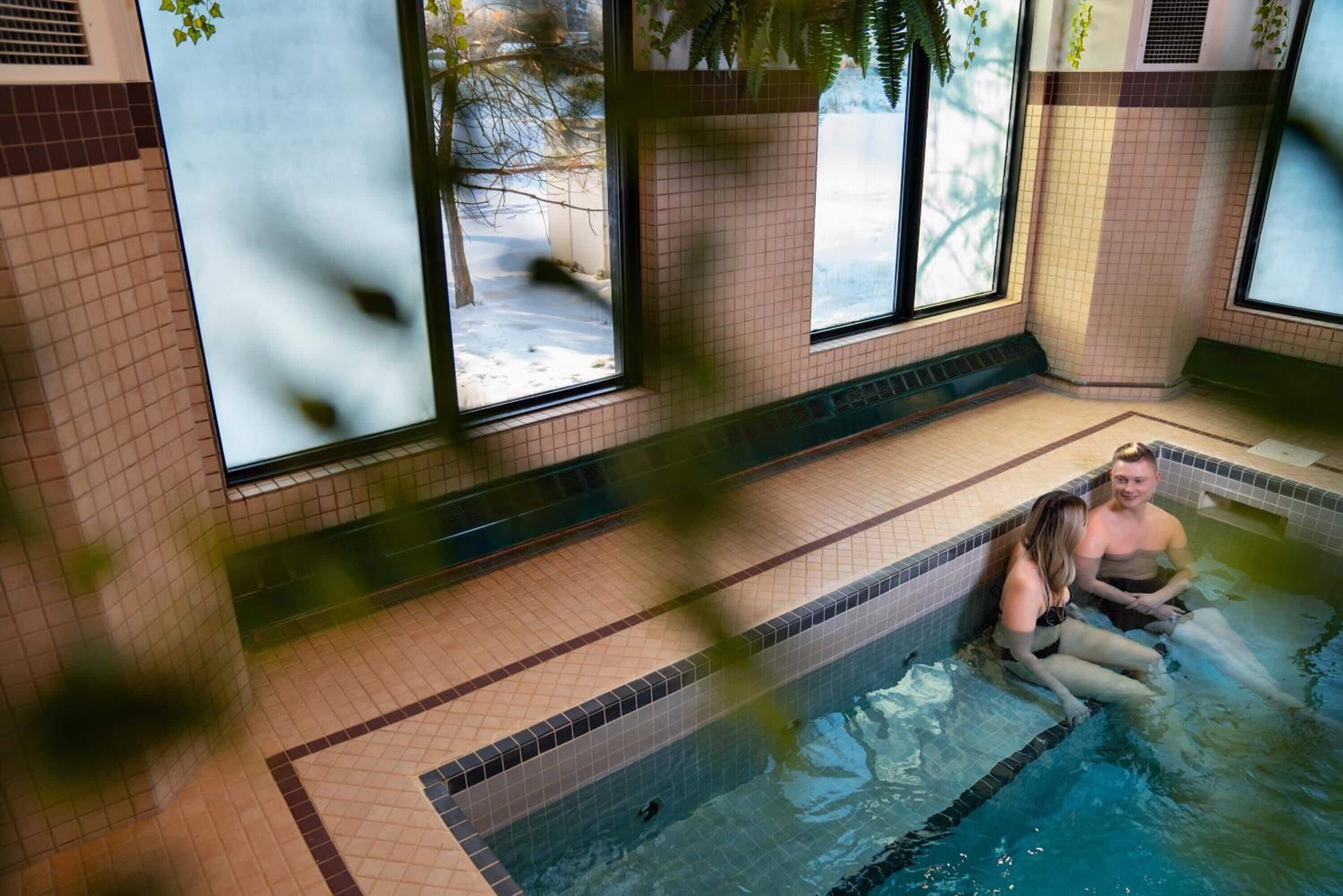 Un área de piscina con suelo de baldosas y grandes ventanales.