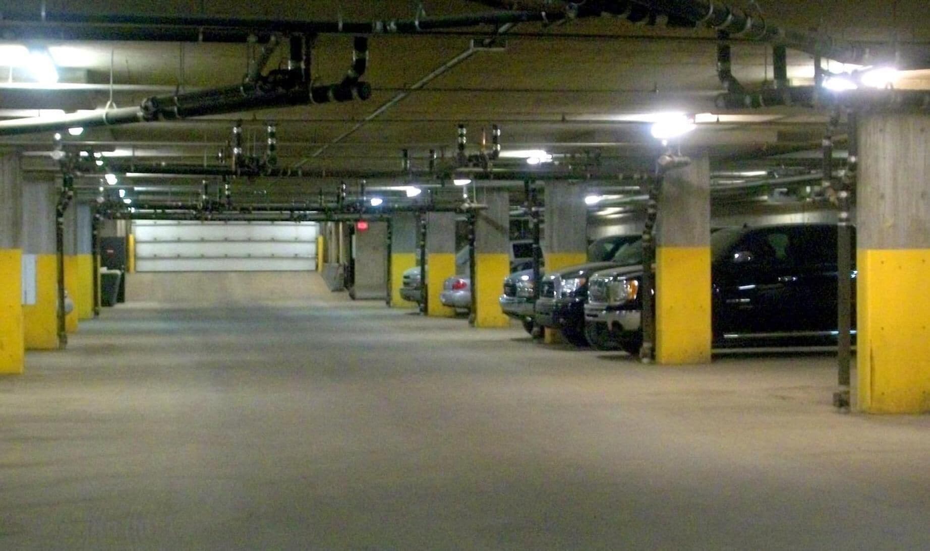 Un parcheggio sotterraneo su più livelli, con pilastri in cemento e segnaletica di sicurezza gialla.