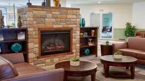 A lobby with a stone fireplace, leather sofas, and a coffee table. - Clearwater Suite Hotel (Fort McMurray)