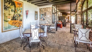 Un restaurante con paredes de piedra, sillas de estructura metálica y un cartel grande en la pared.