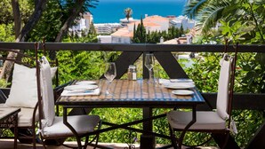 Una mesa para dos con vista al océano y edificios al fondo.