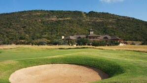 Un terrain de golf avec un bunker de sable et, au fond, un bâtiment surmonté d’une tour.