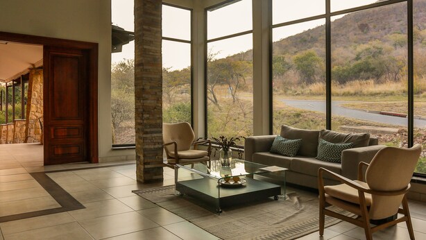 Un salon spacieux avec une grande table basse en verre, des sièges confortables et une vue sur un paysage naturel.