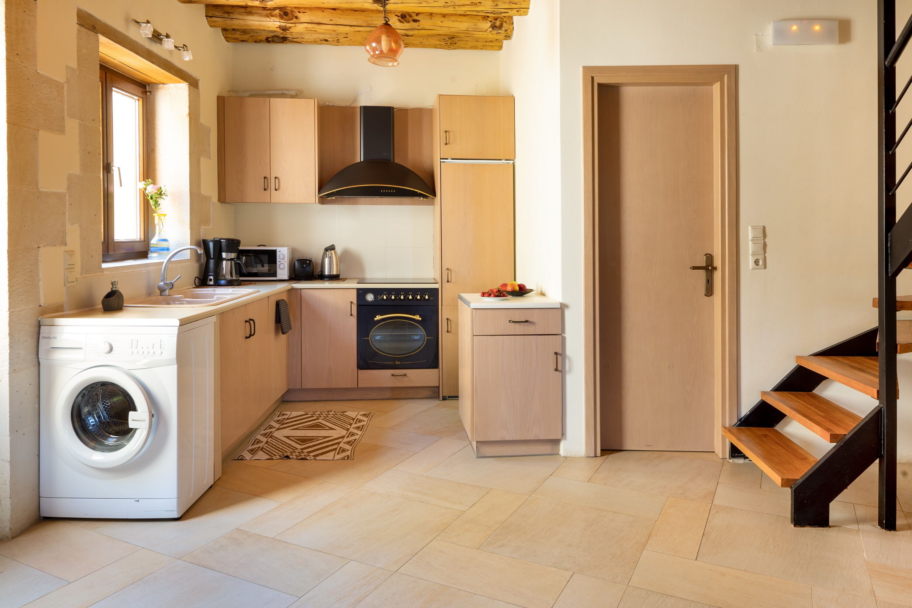 A compact kitchen with a washing machine, oven, microwave, and wooden cabinets.