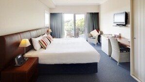 A hotel room with a large bed, a desk with a chair, a television, and a balcony with a chair. - Seashells Yallingup (Yallingup)