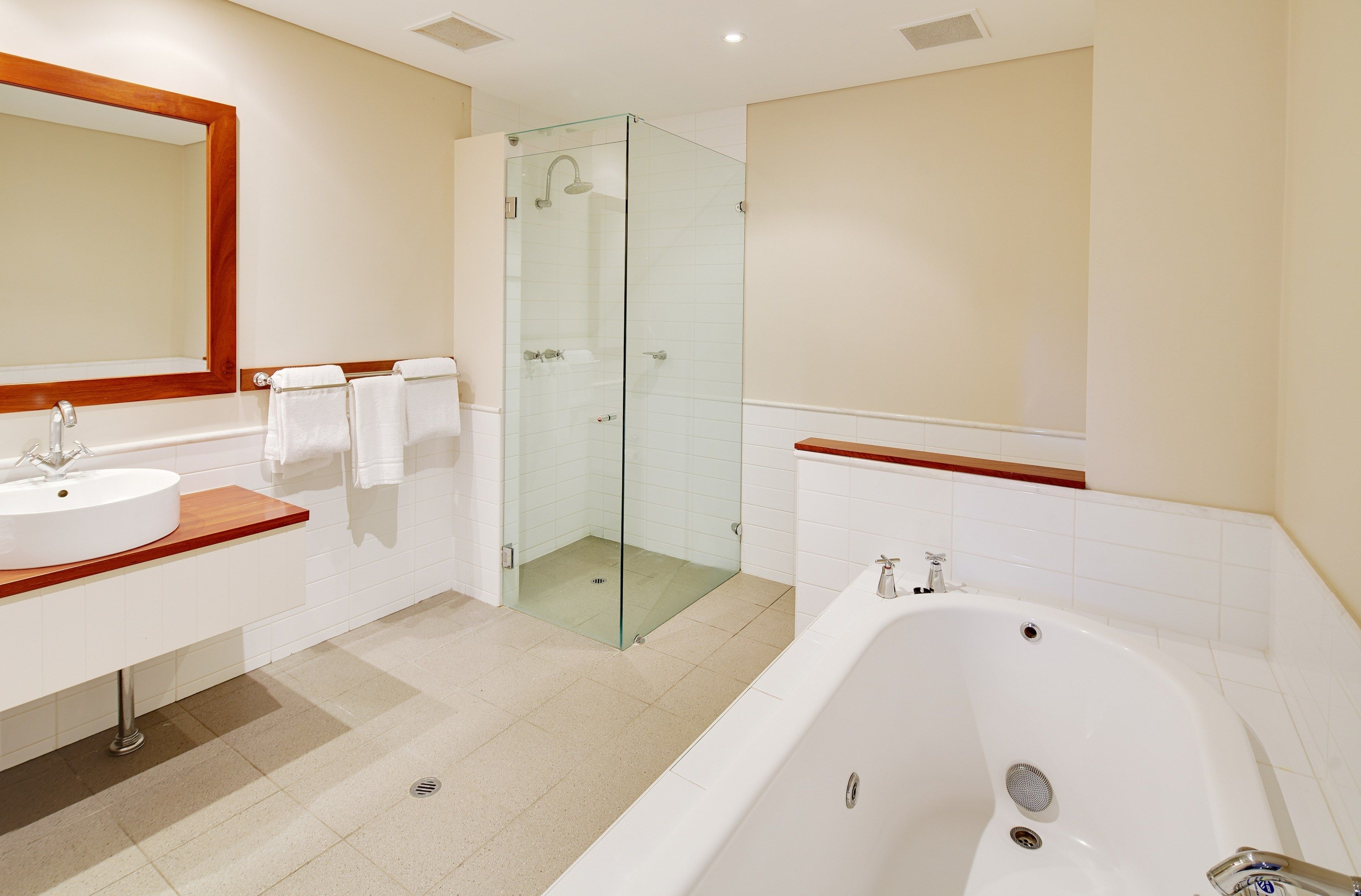 Ein modernes Badezimmer mit einer gläsernen Duschkabine, einer großzügigen Badewanne und einem Waschtisch mit Spiegel und Waschbecken.