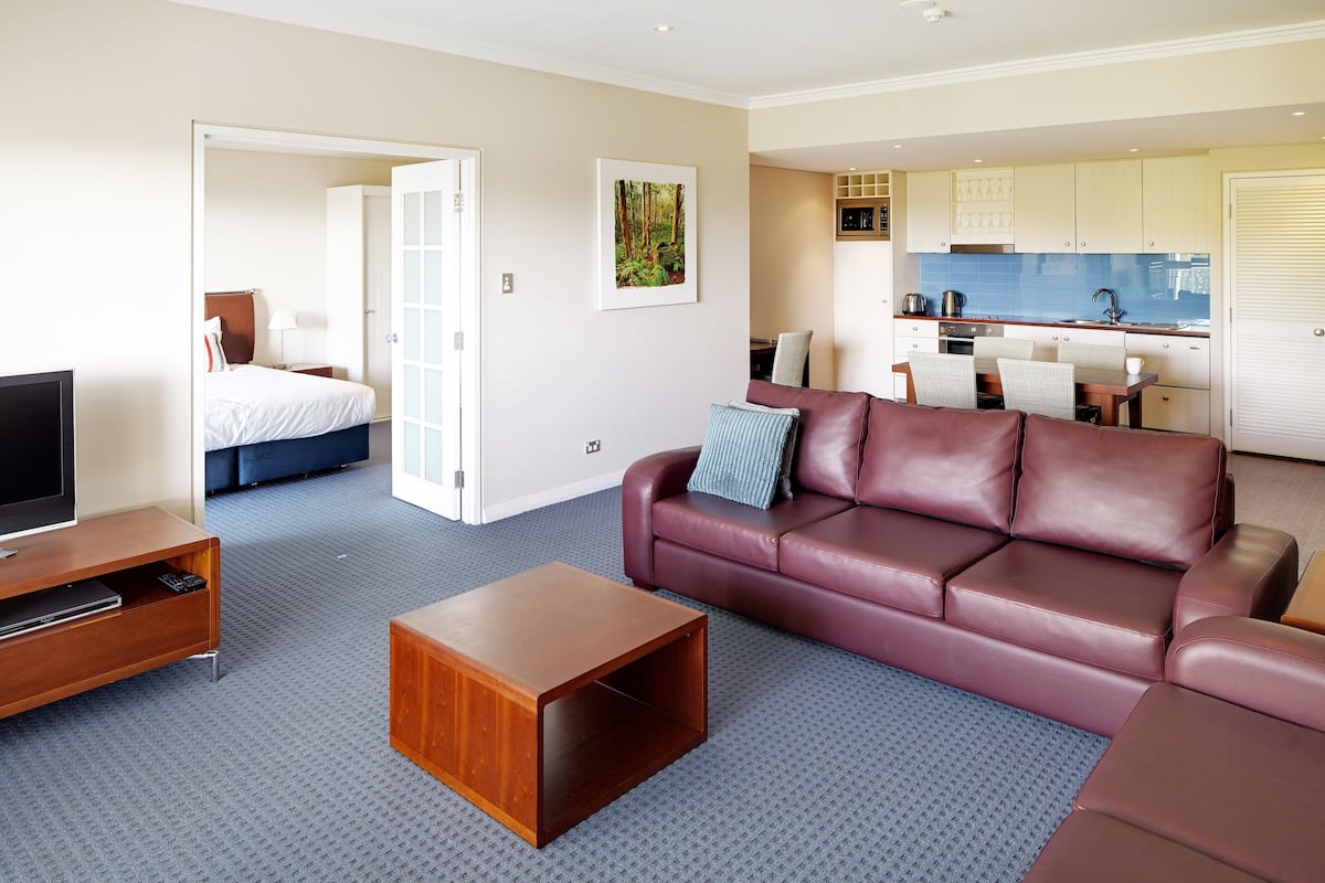 Una habitación de hotel moderna con sala de estar, un dormitorio independiente, kitchenette y baño.