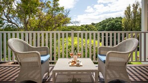 A wicker table with two chairs on a deck, a bottle, and a glass of wine. - Seashells Yallingup (Yallingup)