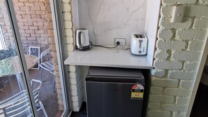 Una cocina compacta con un refrigerador, un tostador y una tetera sobre la encimera.