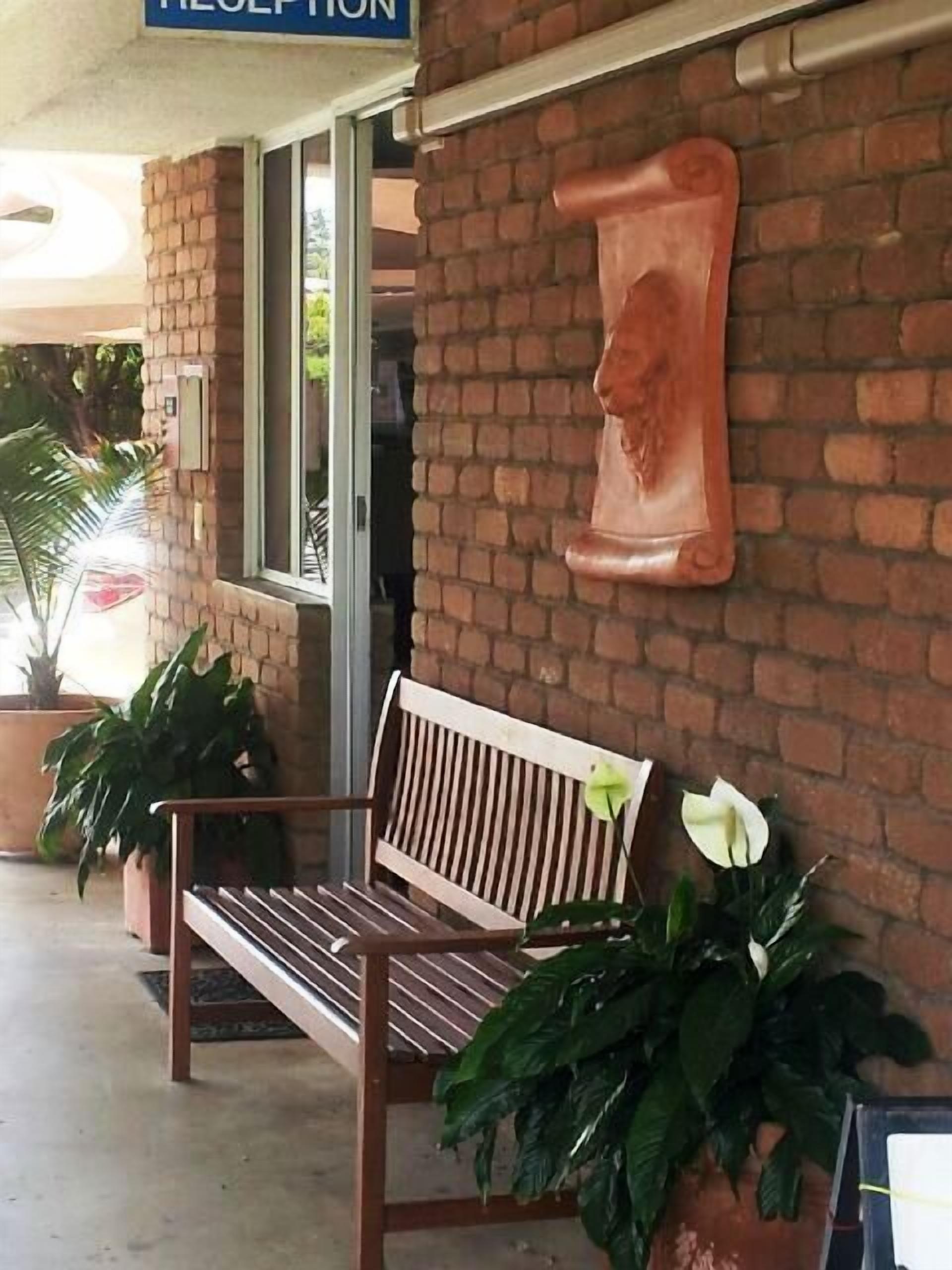 A reception area with a wooden bench, potted plants, and a brick wall.