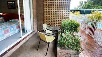 Een balkon met een bed, een tafel, stoelen en een bloempot.