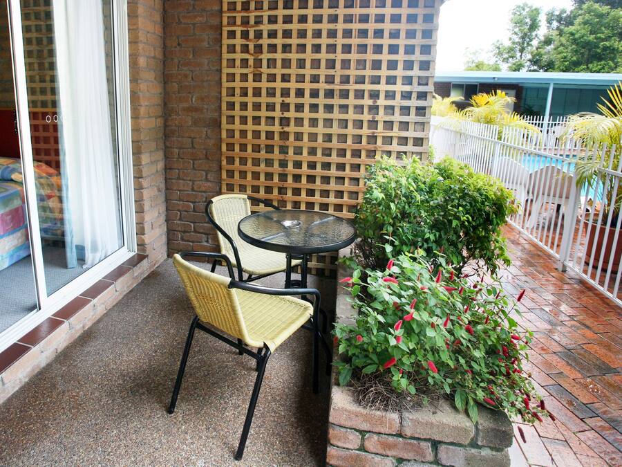 Een balkon met een bed, een tafel, stoelen en een bloempot.