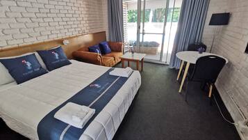 A hotel room with a large bed, a sofa, a small table, and a desk.