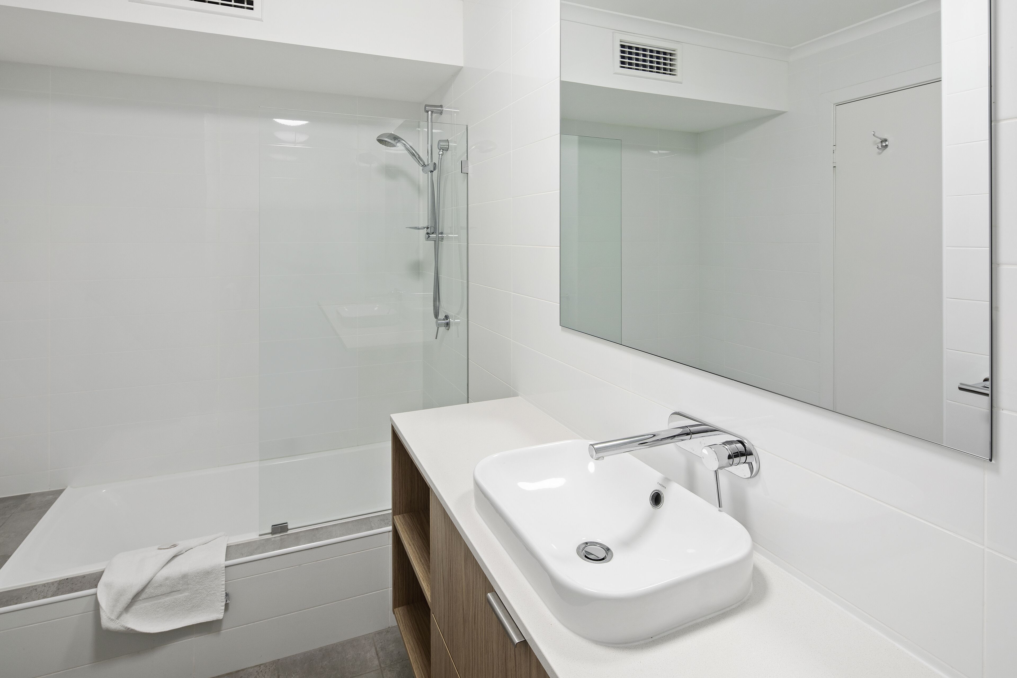 A modern bathroom with a glass-enclosed shower, a white sink, and a large mirror.