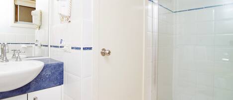 A bathroom with a white sink, blue countertop, and a glass shower enclosure.