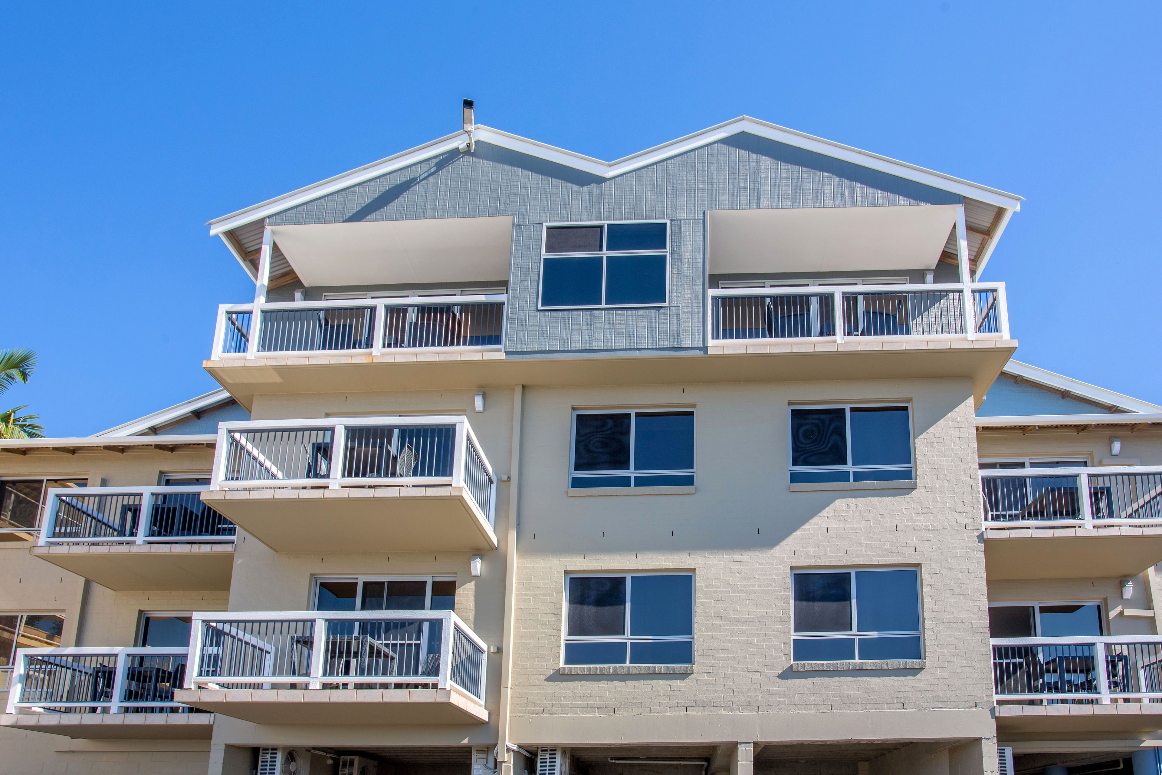 Un edificio residencial de varios pisos con balcones, ventanas amplias y techo plano.