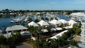 Un port de plaisance où sont amarrés de nombreux bateaux, entouré d’immeubles résidentiels aux toits blancs et de palmiers.