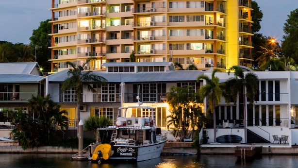 Un hôtel à plusieurs étages doté de balcons, avec un bateau amarré devant et une vue sur le front de mer.